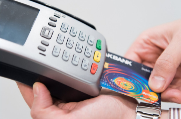 Imagem de uma máquina de cartão de crédito nas mãos de uma pessoa.