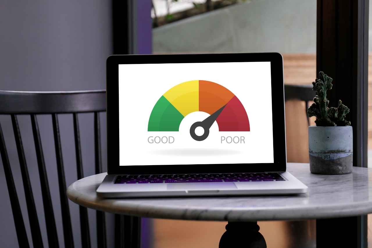 Notebook sobre uma mesa exibindo um medidor colorido de score de crédito, ilustrando como a pontuação financeira influencia a aprovação do empréstimo pessoal sem garantia e comprovante de renda.