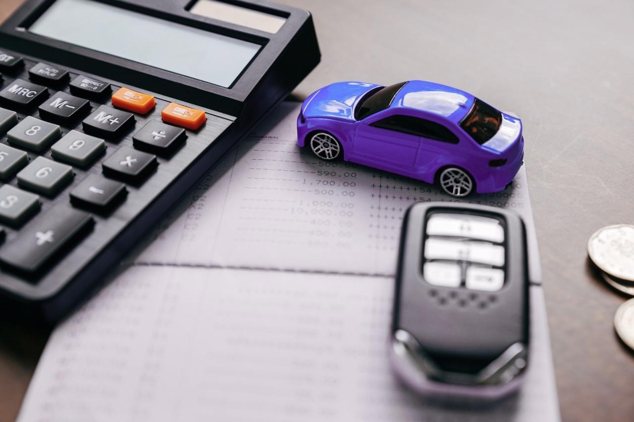Onde fazer empréstimo com garantia de veículo de forma segura? 4 opções e o que avaliar antes de assinar - Juros Baixos Calculadora, miniatura de carro e chave sobre documentos financeiros, representando cálculo de custos e CET no empréstimo com garantia de veículo