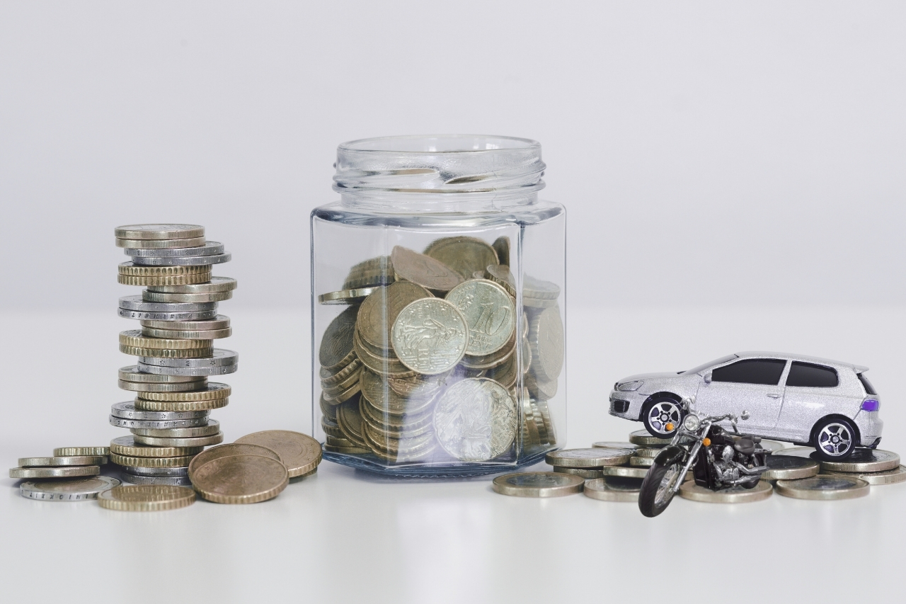 Empréstimo com garantia veicular para autônomos: como comprovar renda - Juros Baixos Pote de moedas ao lado de miniaturas de carro e moto, simbolizando uso de veículo como garantia em empréstimo com garantia veicular