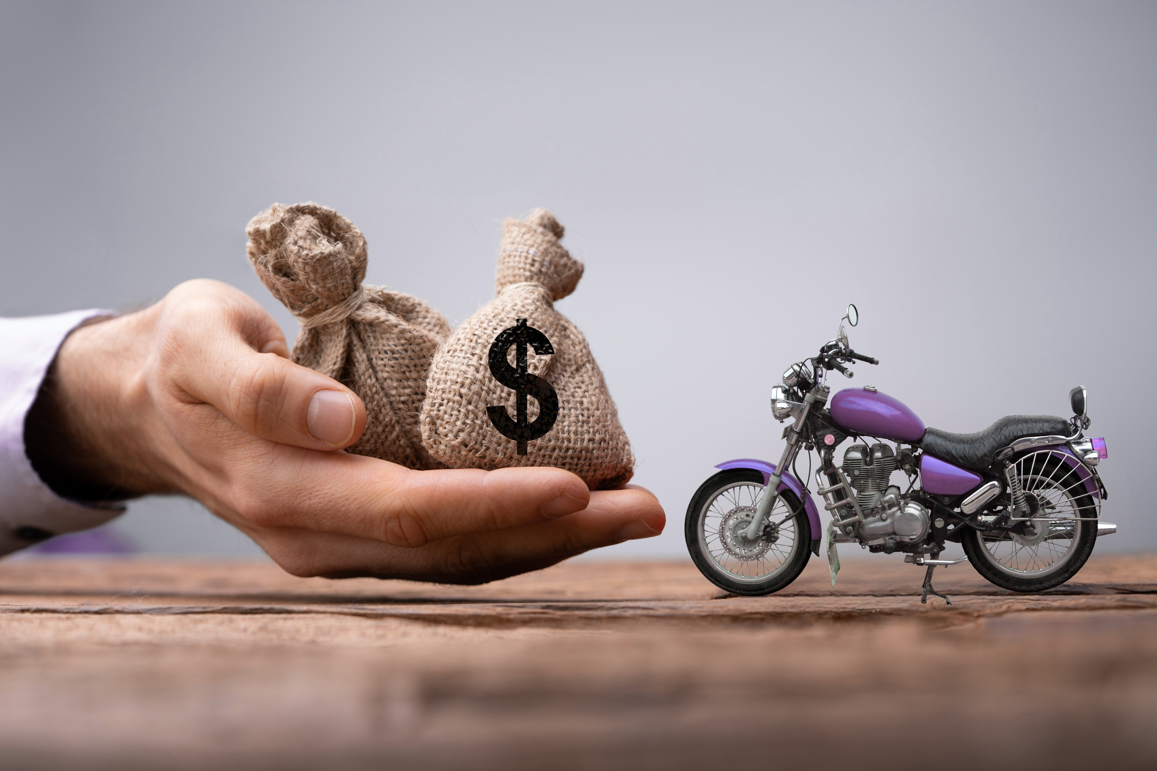 Comparação entre empréstimo com garantia de moto e empréstimo pessoal, com sacos de dinheiro e motocicleta representando custo, parcela e crédito